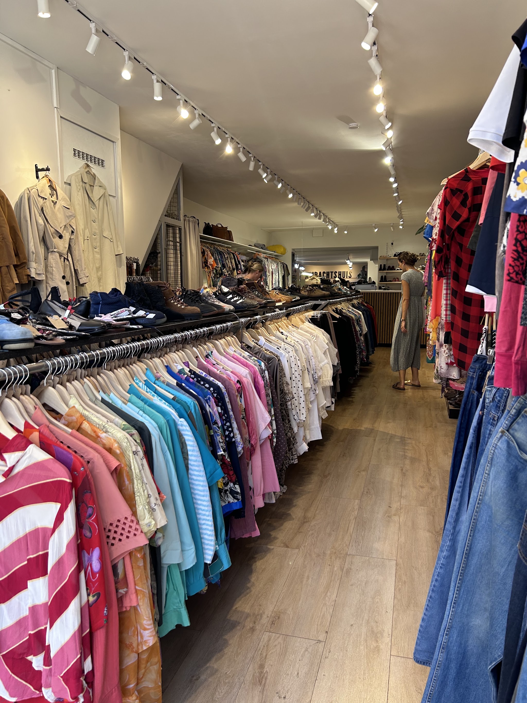 Rekken met vintage overhemden, jassen en schoenen in de winkel