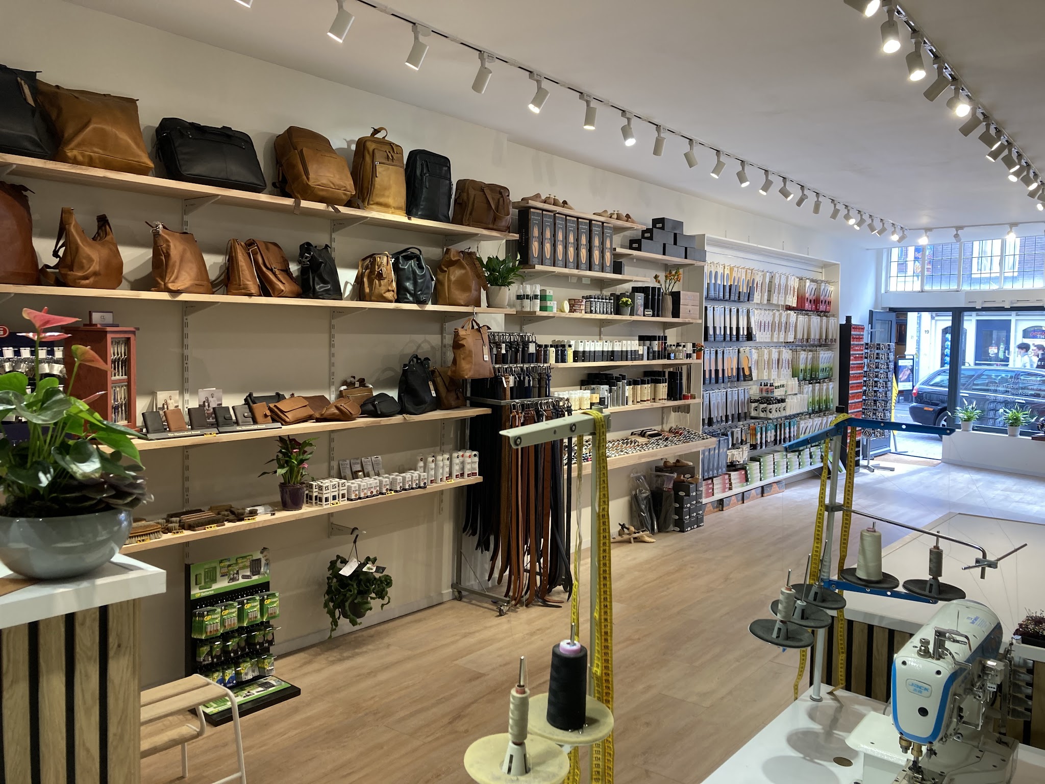 De winkel met planken vol tassen, riemen en verzorgingsmiddelen, rechts de naaitafel