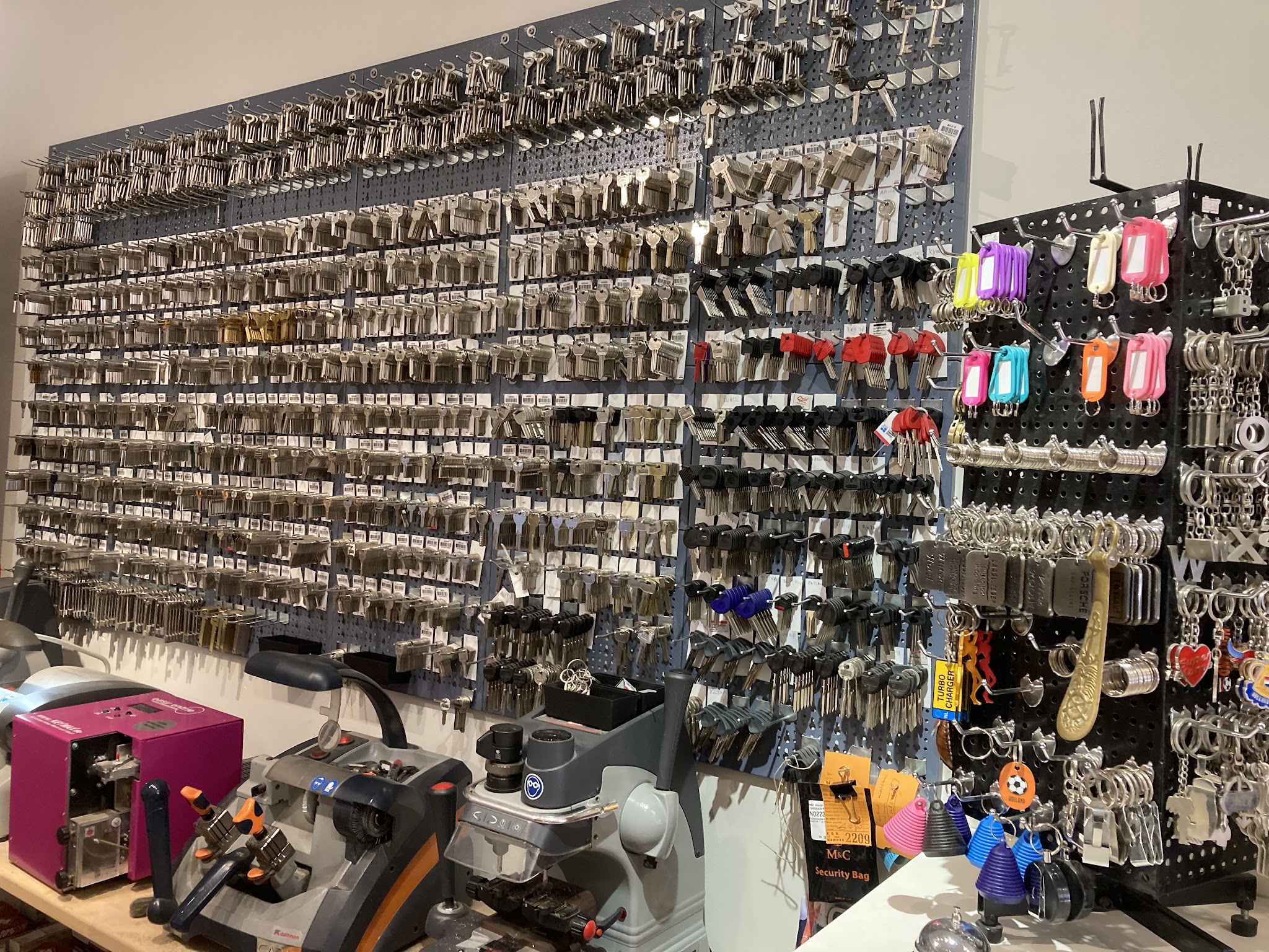 De sleutelwand met honderden sleutelbaarden en de sleutelmachine op de toonbank